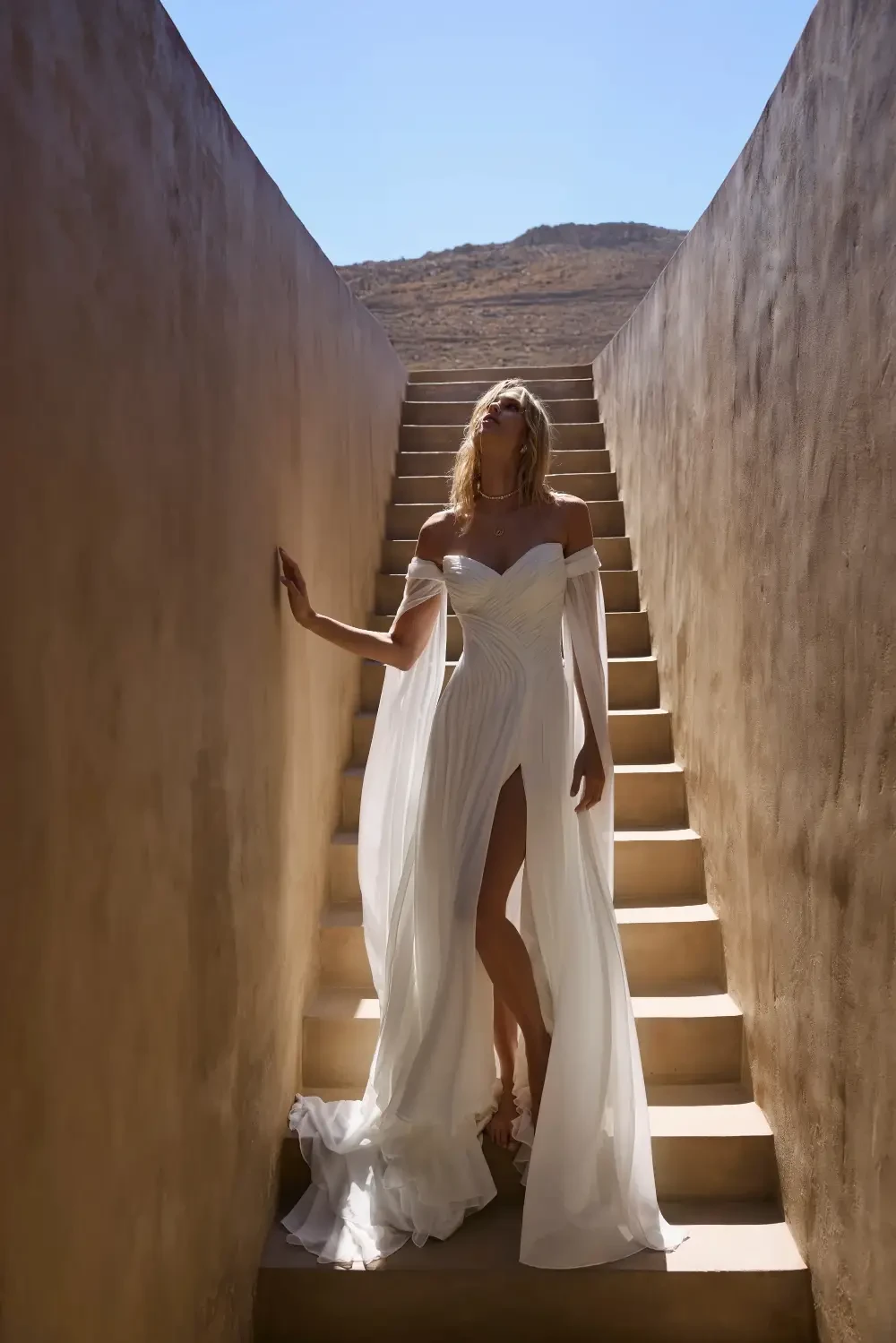 model is wearing an off the shoulder breezy bridal gown