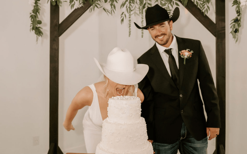 a bride and a groom at the reception eating their wedding cake