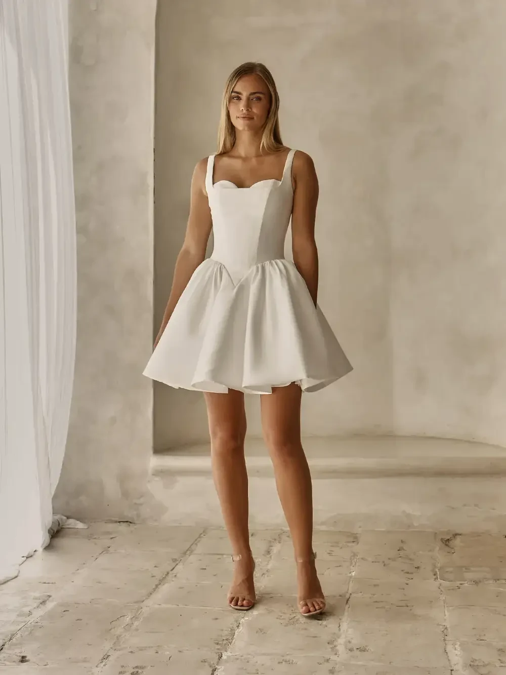 model is wearing a sleeveless mini bridal gown
